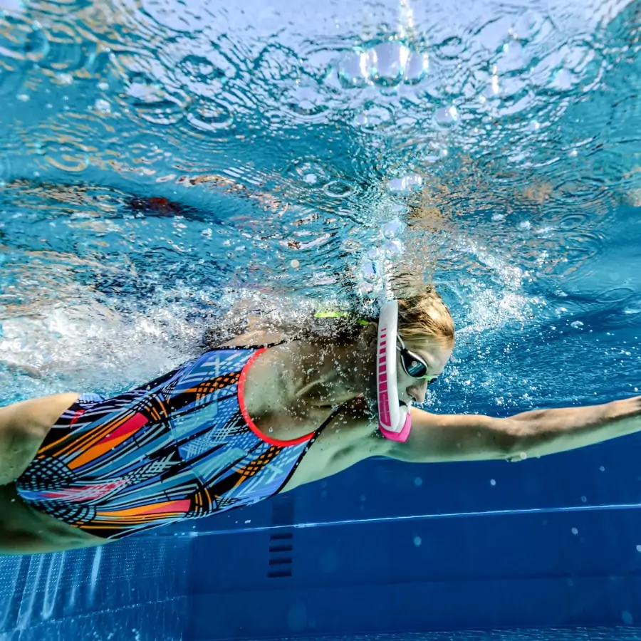 Schwimmerin mit AMEO Powerbreather beim Kraulschwimmen unter Wasser im Schwimmbecken mit freier Atmung ohne Kopfdrehung